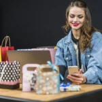 smiling-fashionable-woman-sitting-home-with-shopping-bags-laptop-smartphone
